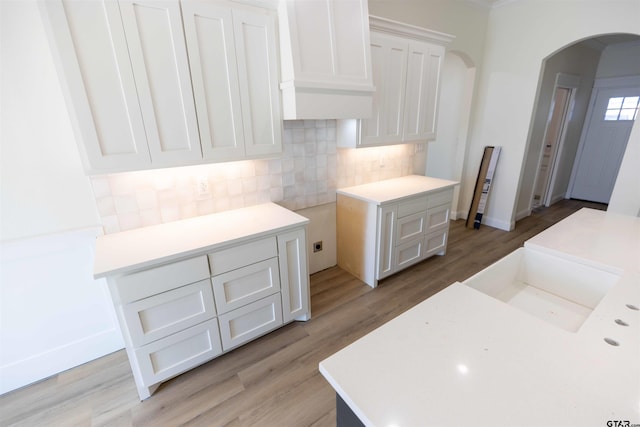 kitchen with backsplash, white cabinetry, and light hardwood / wood-style flooring