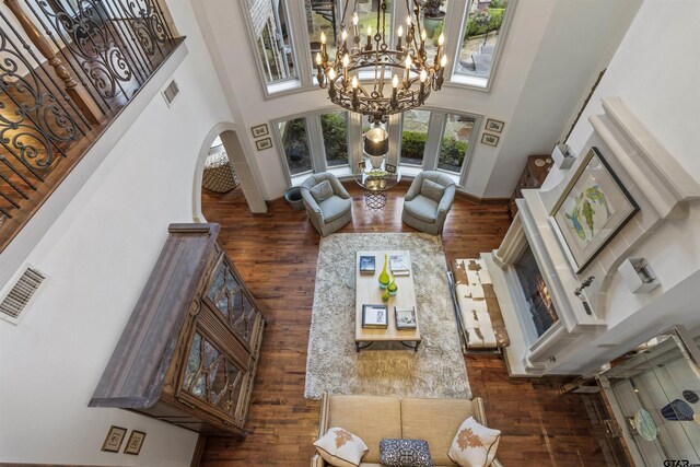 living room featuring dark wood-type flooring, a high ceiling, and a notable chandelier