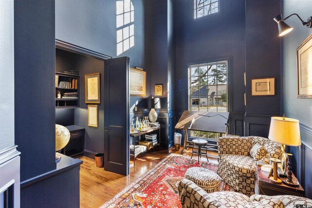 living area featuring plenty of natural light, wood-type flooring, and a towering ceiling