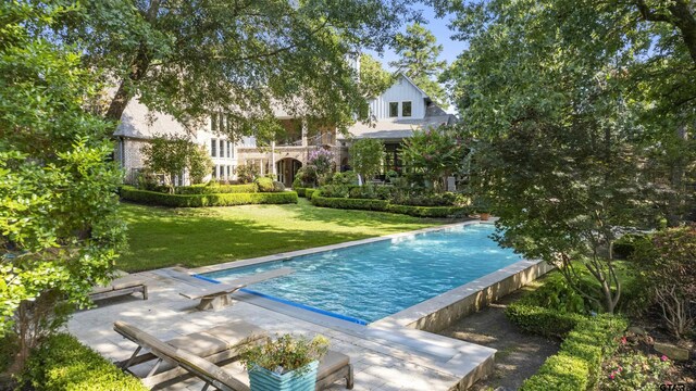 view of pool with a lawn and a diving board