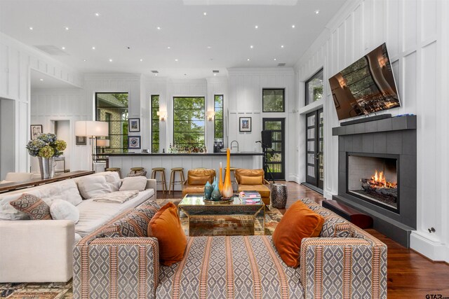 living room featuring a tile fireplace, crown molding, and hardwood / wood-style flooring