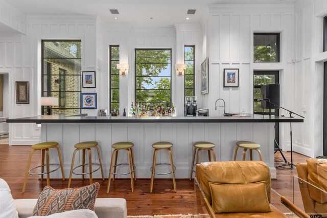 bar featuring white cabinets, light hardwood / wood-style floors, and ornamental molding