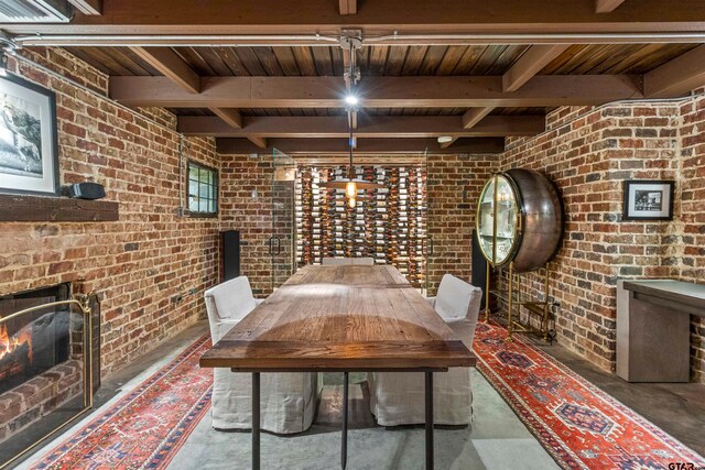 wine area with beamed ceiling, wooden ceiling, brick wall, and a brick fireplace