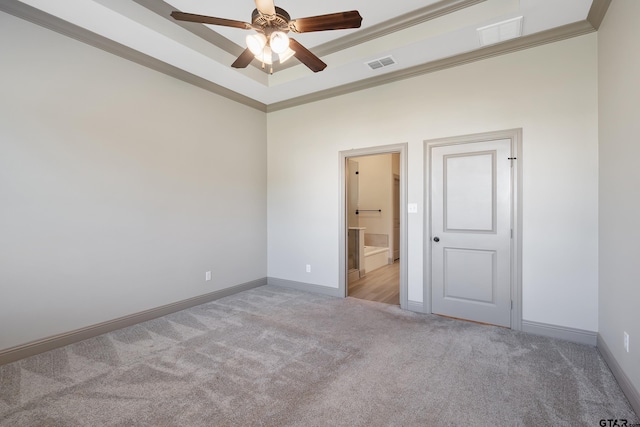 carpeted spare room featuring baseboards, visible vents, a raised ceiling, and ceiling fan