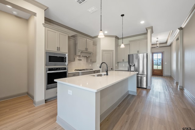 kitchen with backsplash, light countertops, a sink, light wood-style flooring, and appliances with stainless steel finishes