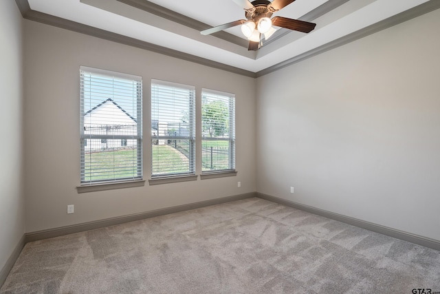 unfurnished room featuring a raised ceiling, baseboards, a ceiling fan, and light colored carpet