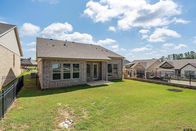 rear view of property with brick siding, a yard, cooling unit, and a fenced backyard