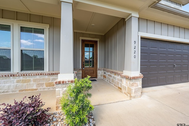 doorway to property with board and batten siding, driveway, a porch, and brick siding