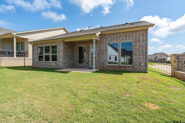 rear view of house featuring a yard, brick siding, fence, and a patio area