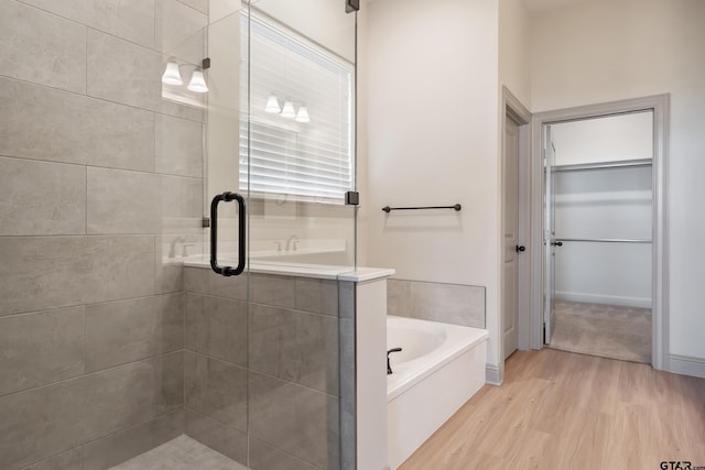 bathroom featuring a garden tub, wood finished floors, and a stall shower