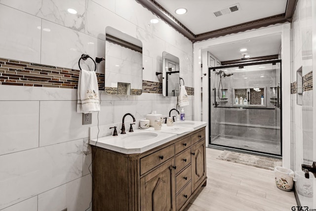 bathroom with crown molding, vanity, tile walls, and walk in shower