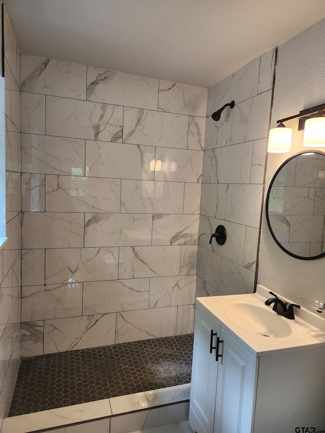 bathroom featuring tiled shower and vanity