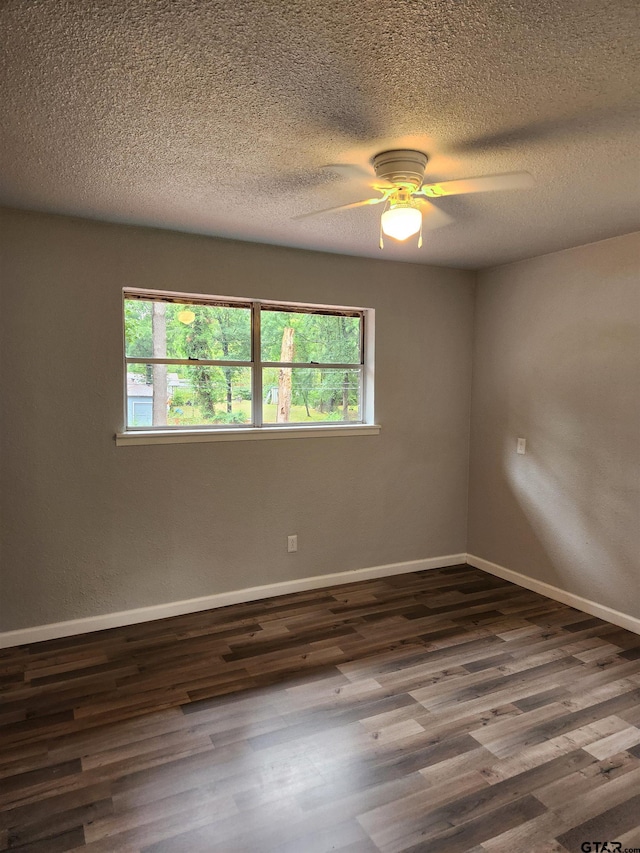 empty room with a textured ceiling, dark hardwood / wood-style flooring, a wealth of natural light, and ceiling fan