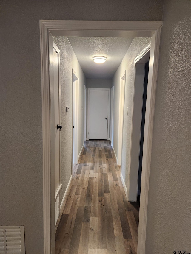 hallway featuring a textured ceiling and hardwood / wood-style flooring