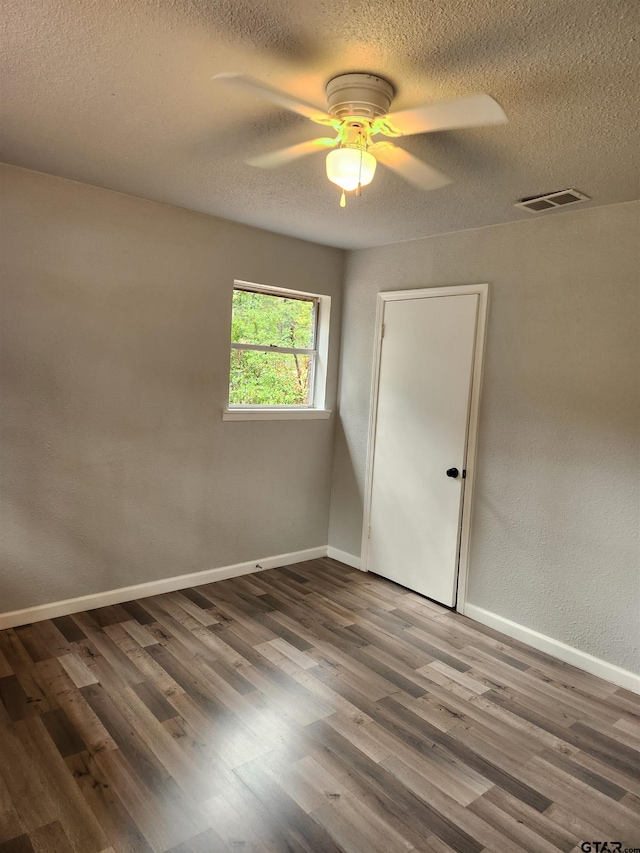 empty room with hardwood / wood-style floors, ceiling fan, and a textured ceiling