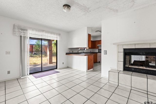 kitchen with kitchen peninsula, a textured ceiling, light tile patterned flooring, and a fireplace