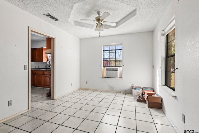 tiled empty room featuring cooling unit, a textured ceiling, and ceiling fan