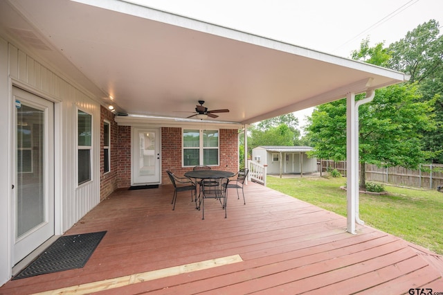 5607 Bostick Dr, Tyler, TX 75707 - wooden terrace with a storage unit, a ceiling fan, outdoor dining space, and an outbuilding