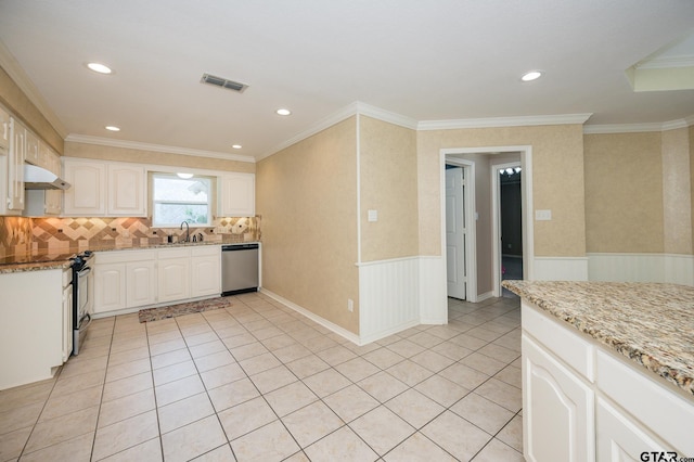 5607 Bostick Dr, Tyler, TX 75707 - kitchen featuring under cabinet range hood, appliances with stainless steel finishes, light stone countertops, a wainscoted wall, and light tile patterned flooring
