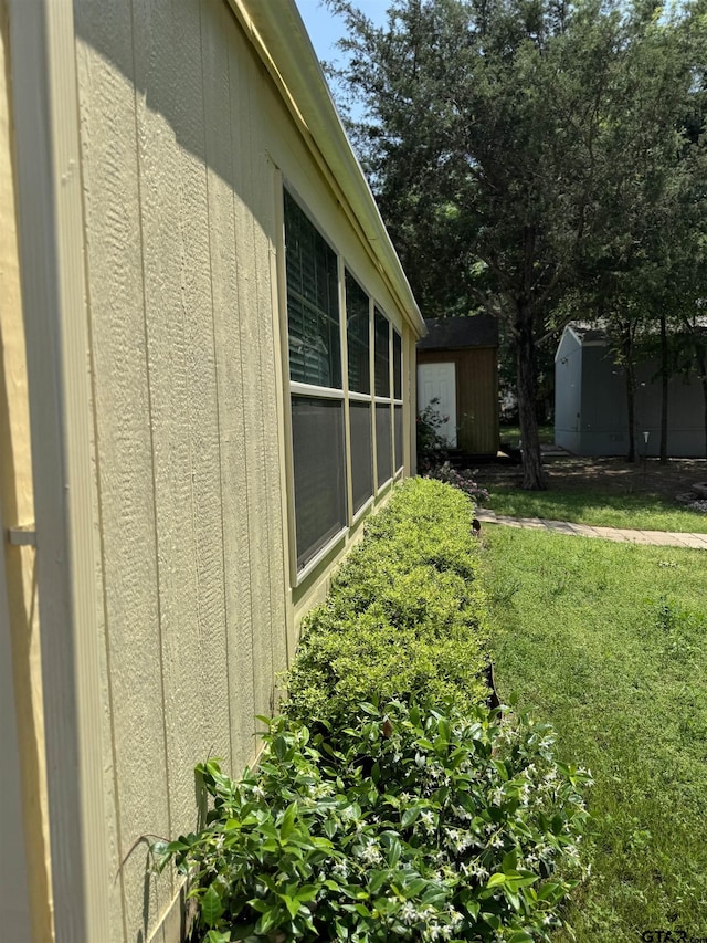 view of side of property featuring an outbuilding, a storage shed, and a yard