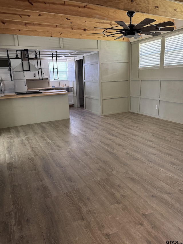 unfurnished living room with ceiling fan, wood finished floors, and a healthy amount of sunlight