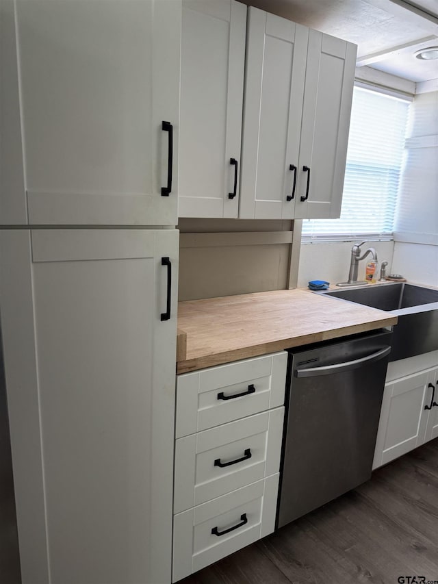 kitchen with stainless steel dishwasher, butcher block countertops, white cabinets, a sink, and dark wood-style floors