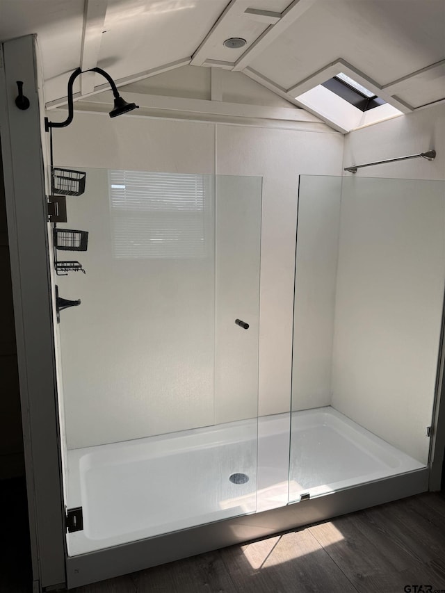 bathroom featuring wood finished floors, a shower stall, and vaulted ceiling