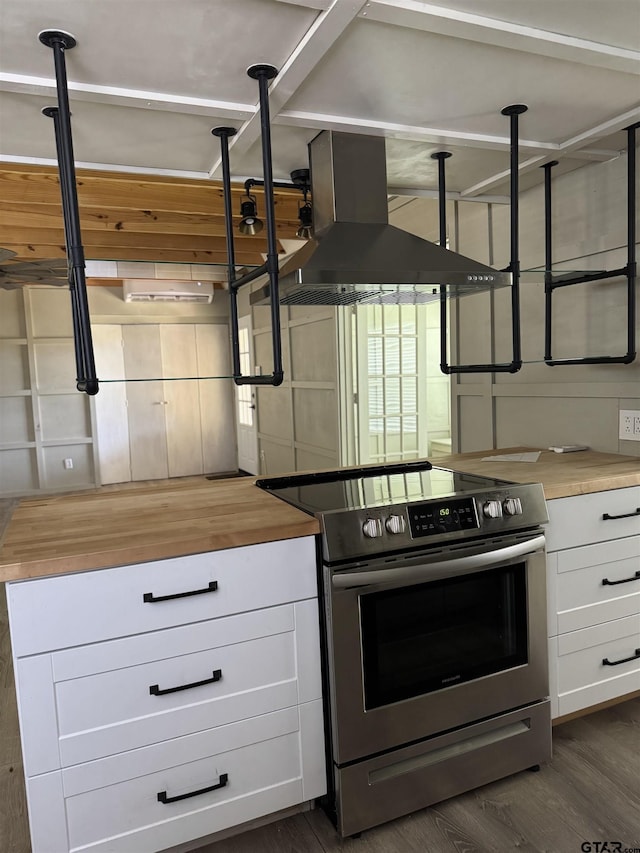 kitchen featuring dark wood finished floors, wood counters, wall chimney exhaust hood, and stainless steel electric range