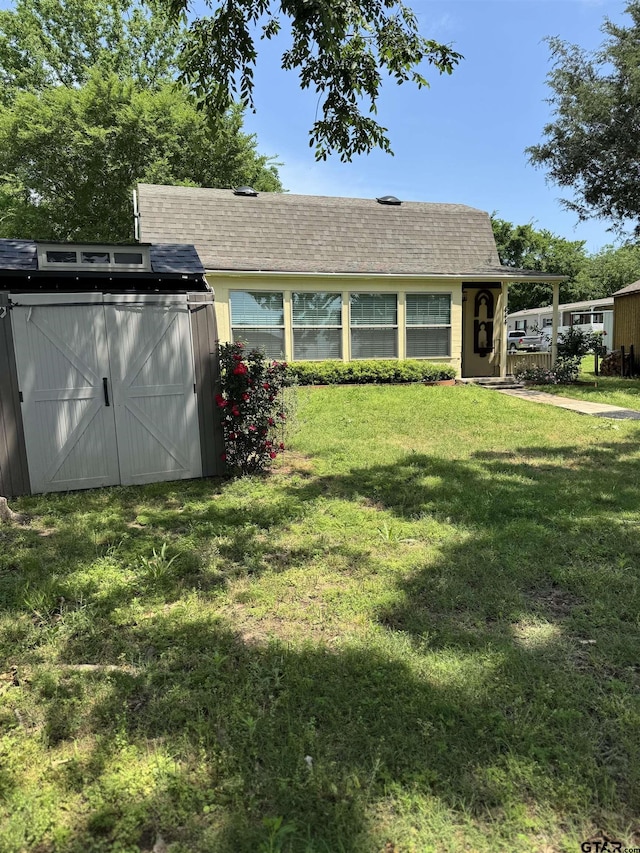 back of property with a lawn and a shingled roof