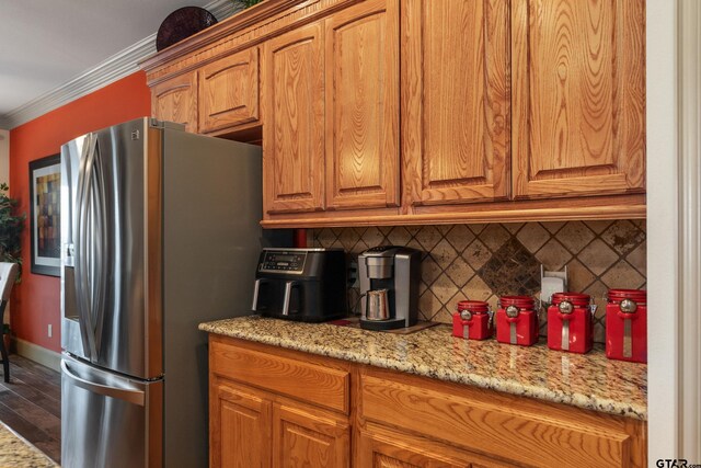 2921 W Alamosa Dr, Terrell, TX 75160 - kitchen featuring stainless steel fridge, backsplash, crown molding, brown cabinets, and light stone counters