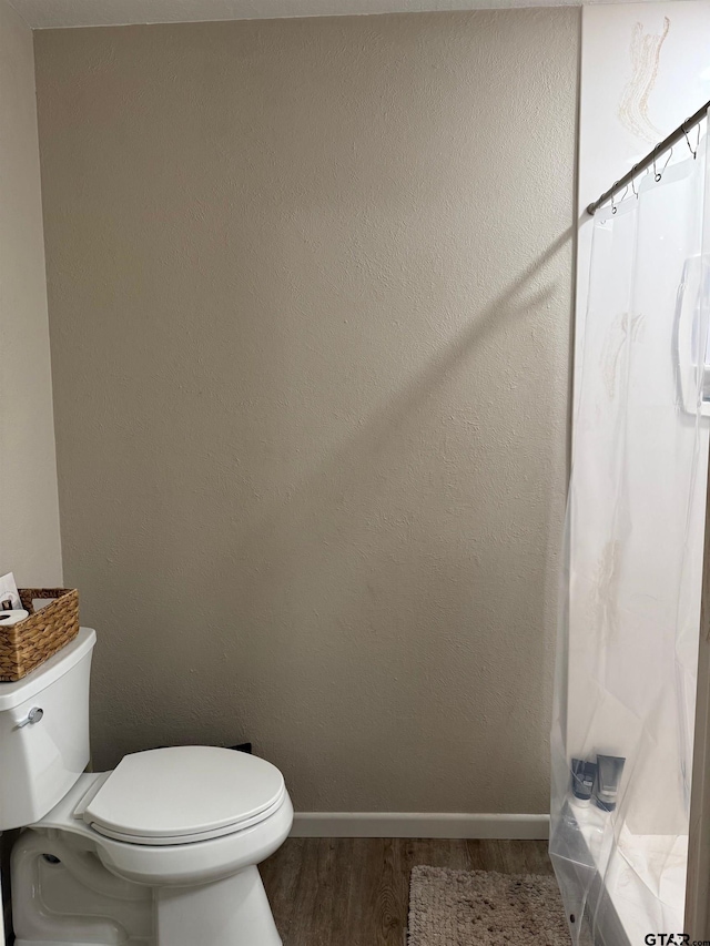 full bathroom featuring a shower with shower curtain, baseboards, toilet, and wood finished floors