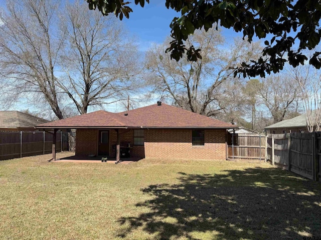 rear view of property with a fenced backyard, brick siding, and a yard