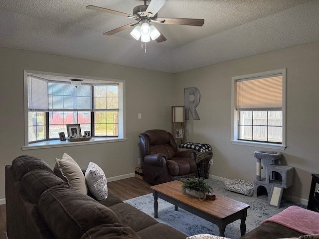 living room featuring plenty of natural light, baseboards, ceiling fan, and wood finished floors