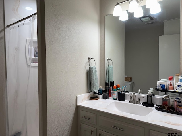 full bathroom with visible vents, vanity, a shower with curtain, and a textured wall