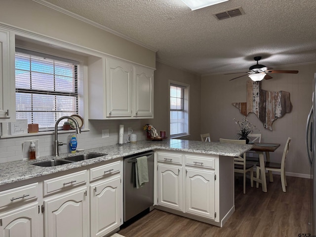 kitchen featuring visible vents, dark wood finished floors, a peninsula, stainless steel dishwasher, and a sink