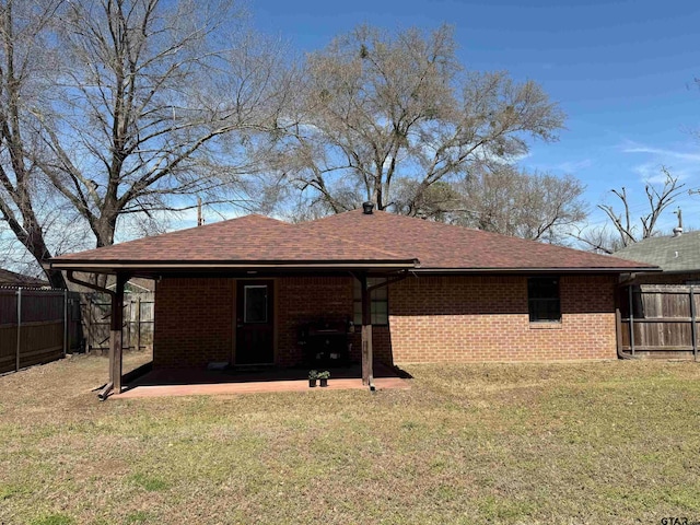 rear view of house with brick siding, a patio area, a yard, and fence