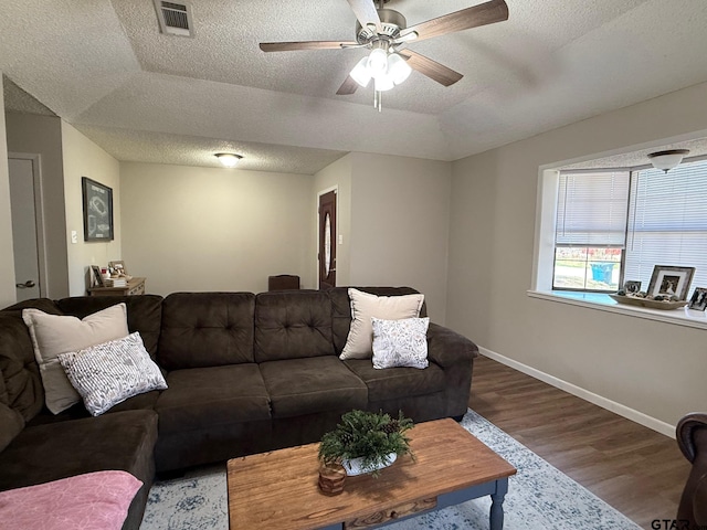 living room with visible vents, a ceiling fan, a textured ceiling, wood finished floors, and baseboards