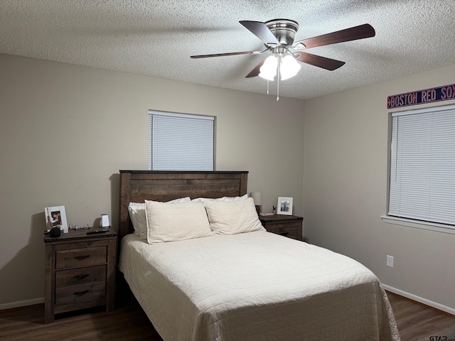 bedroom with a textured ceiling, dark wood-type flooring, baseboards, and a ceiling fan