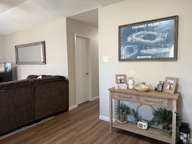 corridor featuring wood finished floors, baseboards, and a textured ceiling