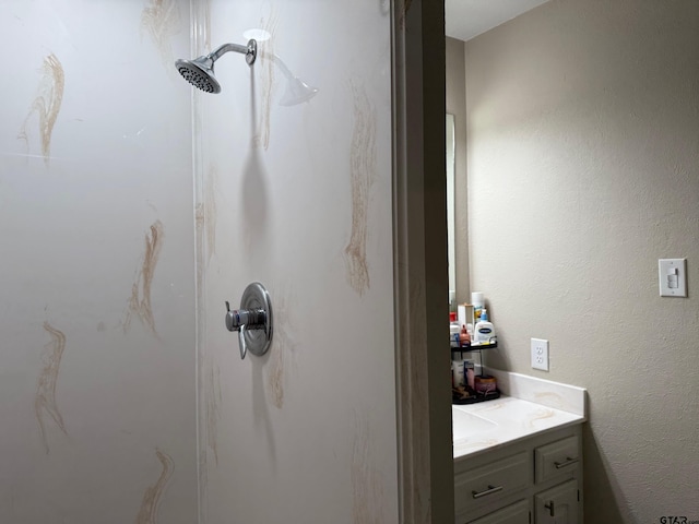 bathroom featuring a marble finish shower and vanity