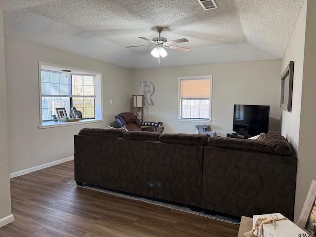 living room with dark wood finished floors, a ceiling fan, baseboards, and a wealth of natural light