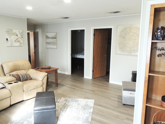 living room featuring light hardwood / wood-style flooring, a textured ceiling, and crown molding