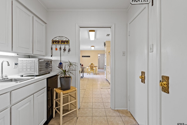 1901 Livingston St, Longview, TX 75601 - kitchen with a sink, white cabinets, ornamental molding, light tile patterned floors, and light countertops