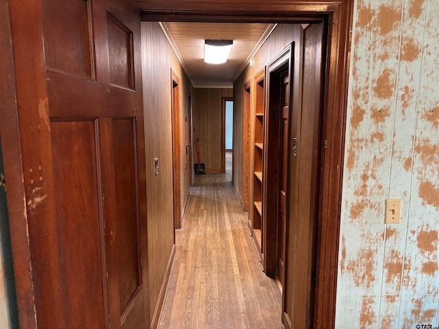 corridor with light hardwood / wood-style flooring and ornamental molding