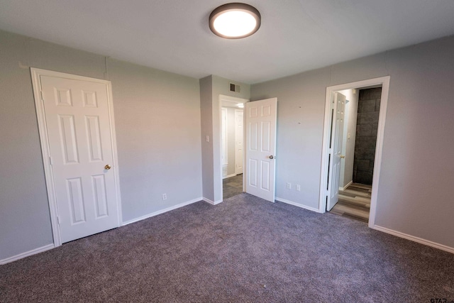 unfurnished bedroom with visible vents, dark carpet, connected bathroom, and baseboards