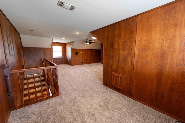 bonus room featuring wood walls, ceiling fan, and light colored carpet