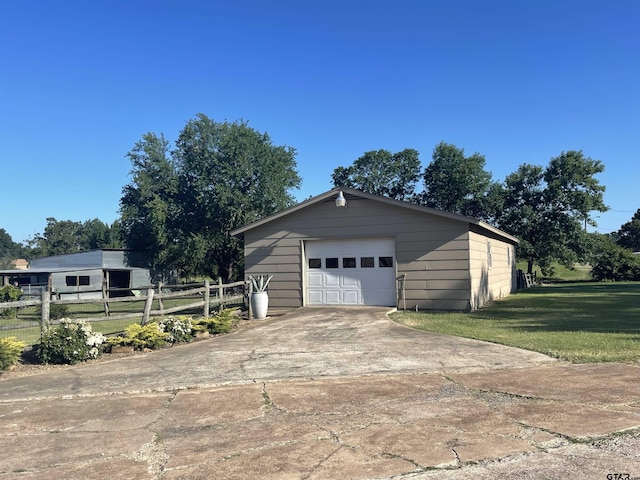 detached garage featuring fence and driveway