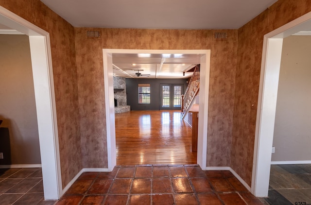 hallway with visible vents, stairs, and baseboards