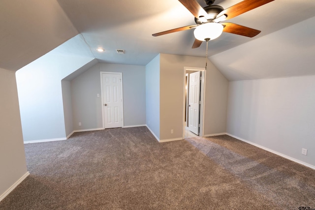 additional living space with ceiling fan, dark carpet, and vaulted ceiling