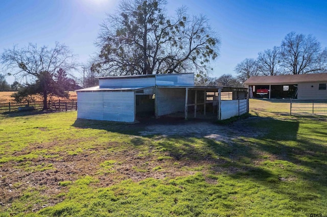 view of pole building featuring driveway, a carport, a lawn, and fence